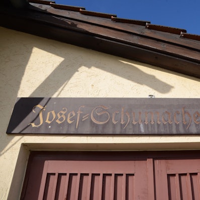 Holzschild über einem Halleneingang. "Josef-Schumacher-Halle" steht darauf.