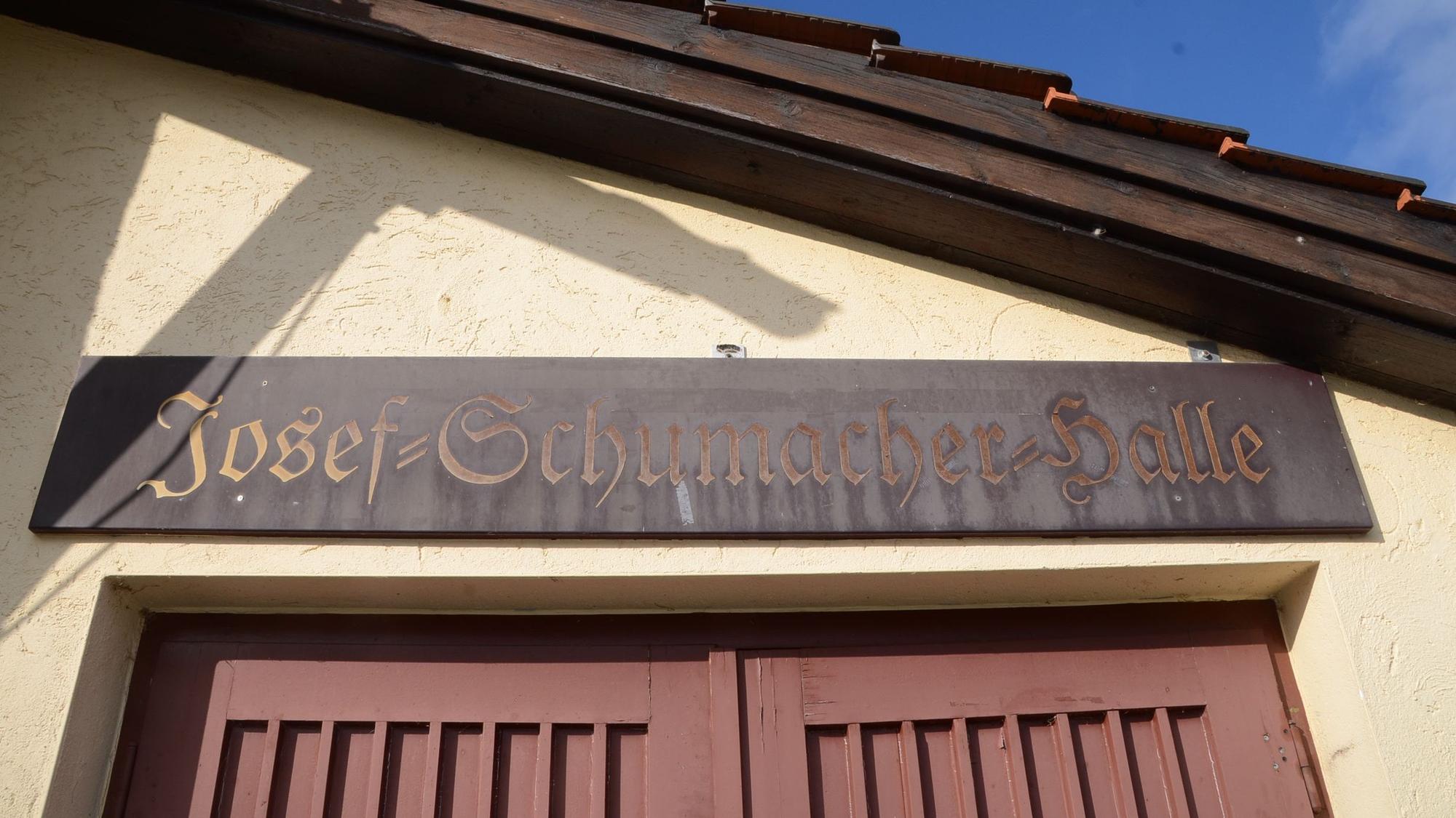 Holzschild über einem Halleneingang. "Josef-Schumacher-Halle" steht darauf.
