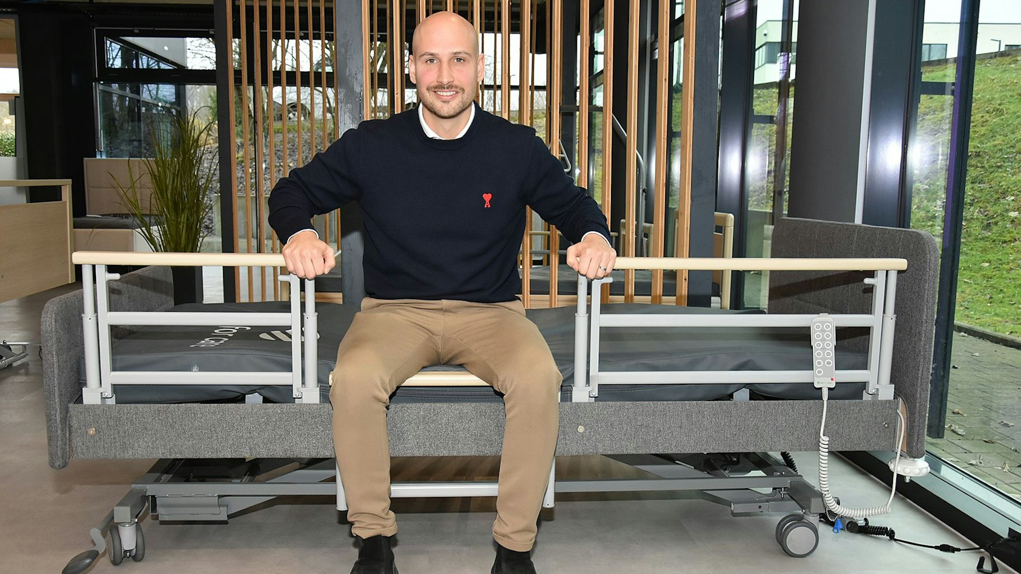 Ein Mann sitzt auf einem Pflegebett.