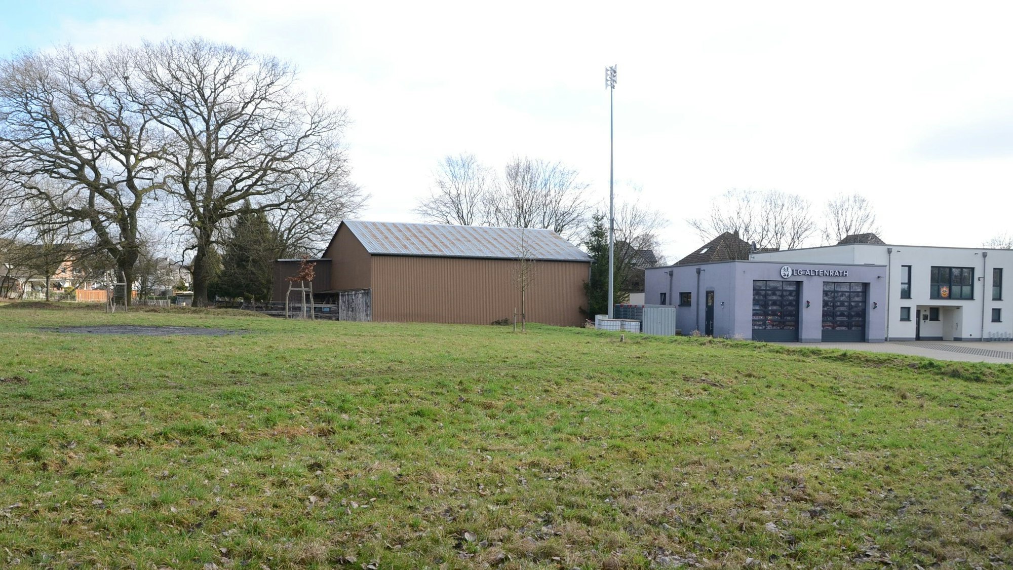 Eine Wiese mit einer Scheune, daneben steht ein Feuerwehrgerätehaus.