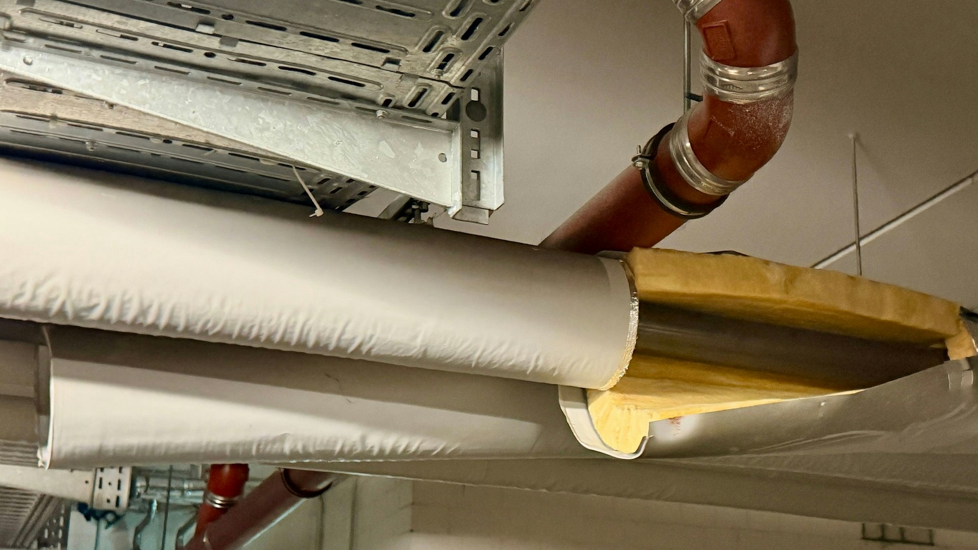 Ein Blick an die Decke der Garage, an der Rohrleitungen verlaufen. An einem Rohr ist die Isolierung beschädigt.