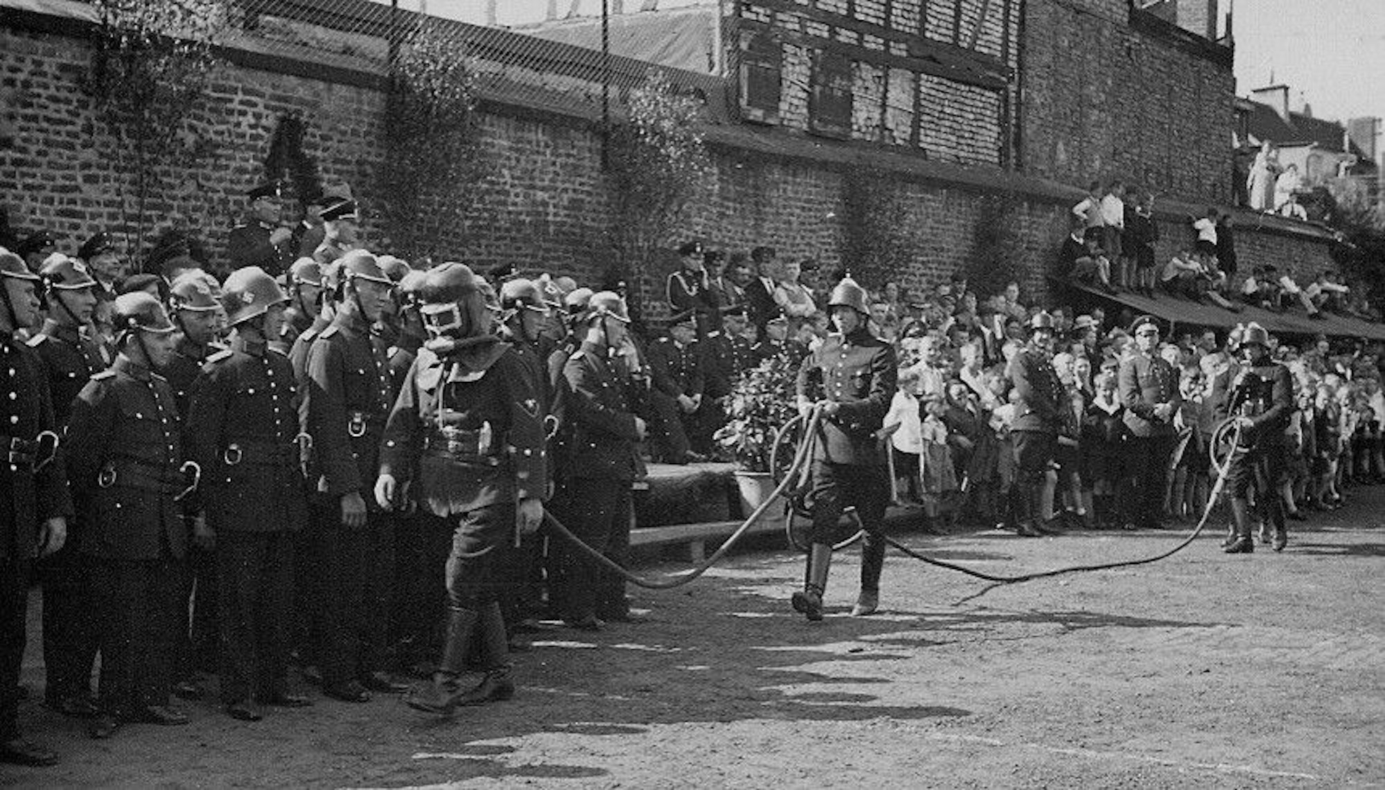 Das Bild zeigt die Vorführung eines ersten Atemschutzgerätes 1936, bei der Hunderte Menschen zuschauten.