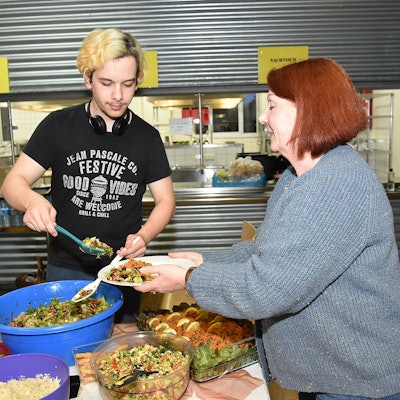 Das Foto zeigt zwei Personen mit einem üppigen Essbuffet.