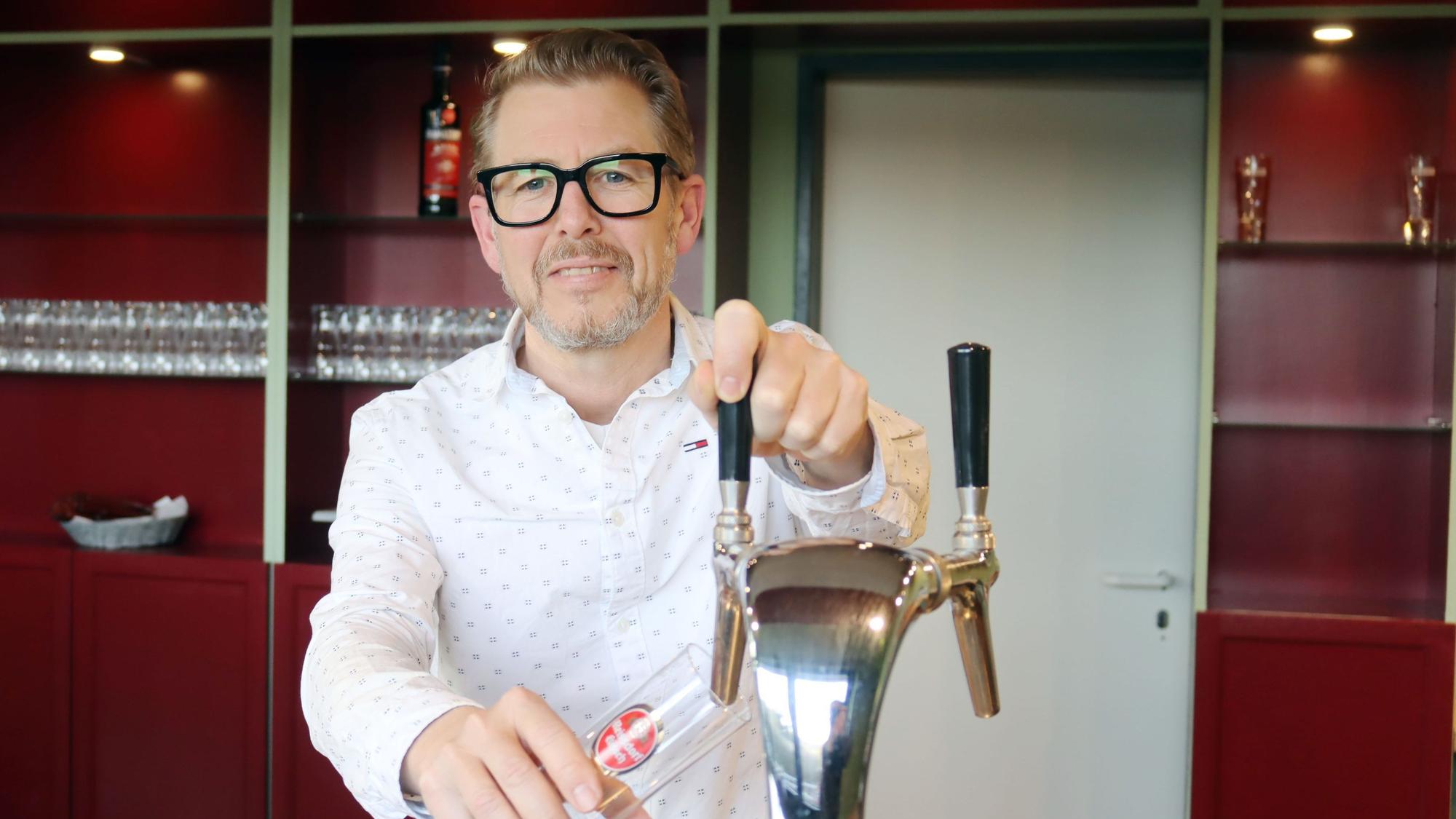 Tilman Wrede steht am Zapfhahn mit einem Kölschglas in der Hand.