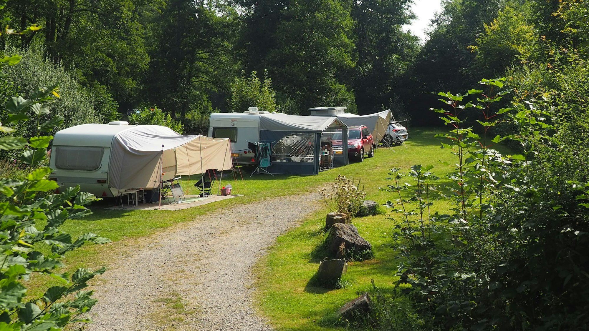 Auf einem Campingplatz stehen mehrere Wohnwagen mit Vorzelten.