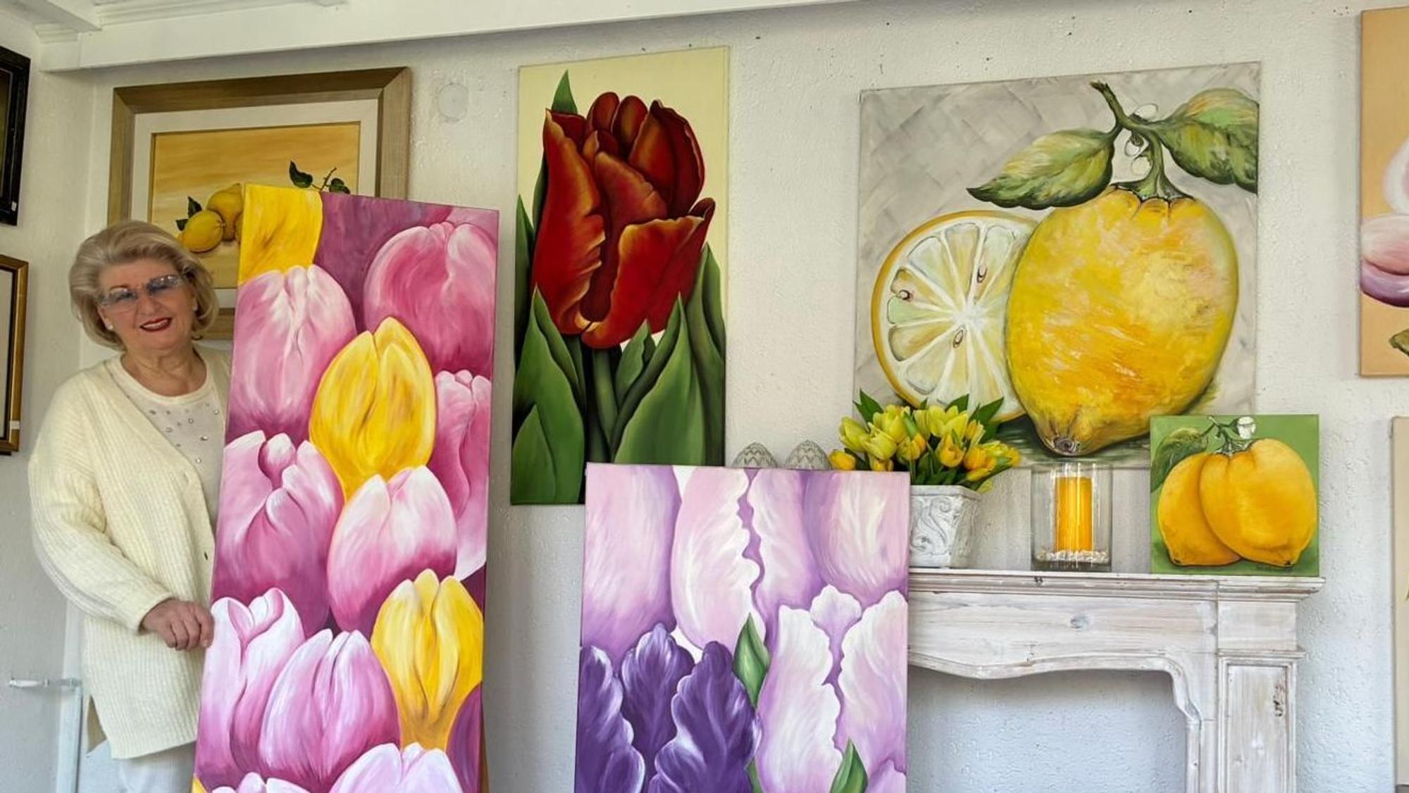 Ellis Paustenbach steht hinter einem Gemälde, das Tulpen zeigt.