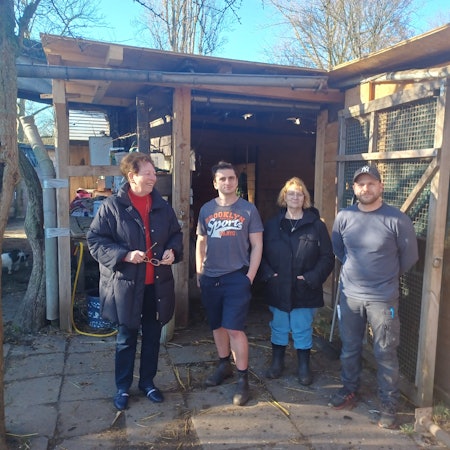 Vier Menschen stehen vor einem Stall.