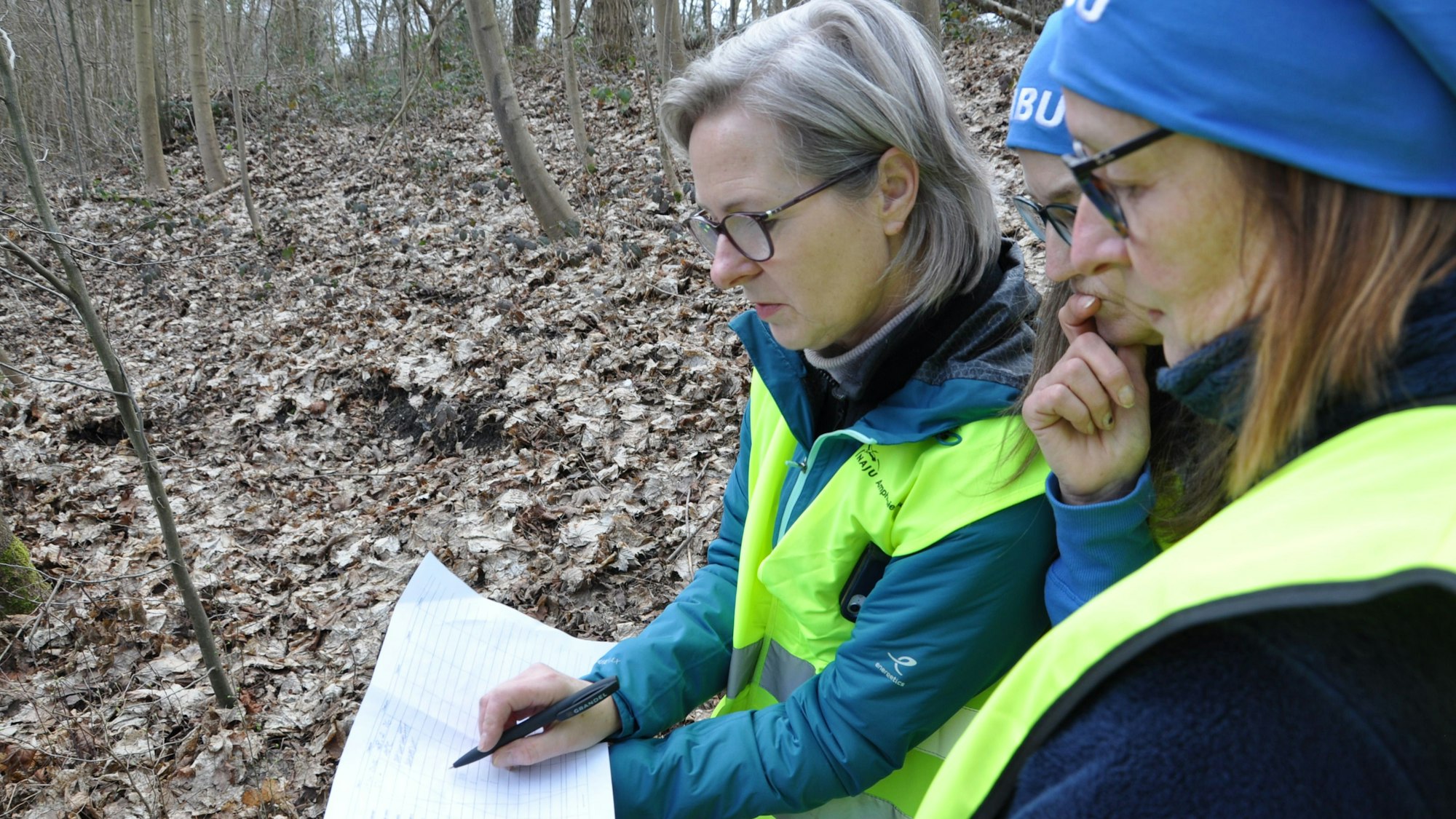 Auf dem Bild sind drei Frauen zu sehen, die eine Liste führen.