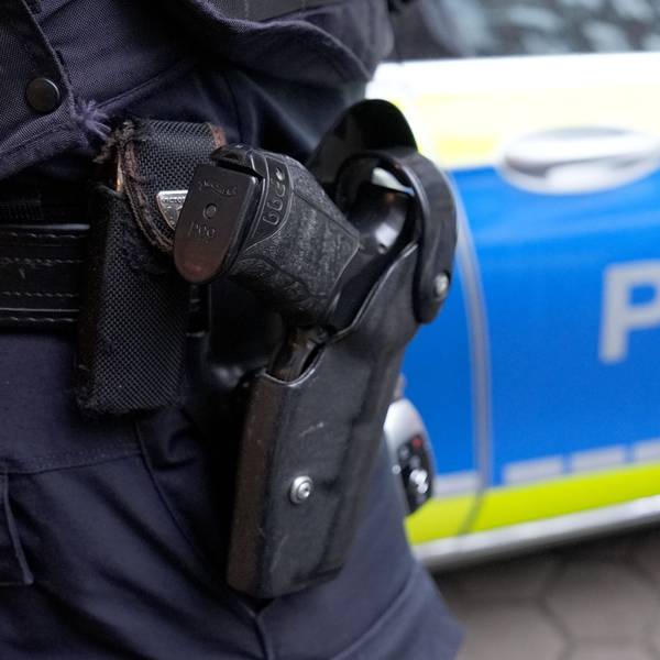 ILLUSTRATION - Ein Polizist steht vor einem Einsatzfahrzeug der Polizei. (zu dpa: «Elfköpfige Gruppe lauert Mann in Sömmerda auf») +++ dpa-Bildfunk +++