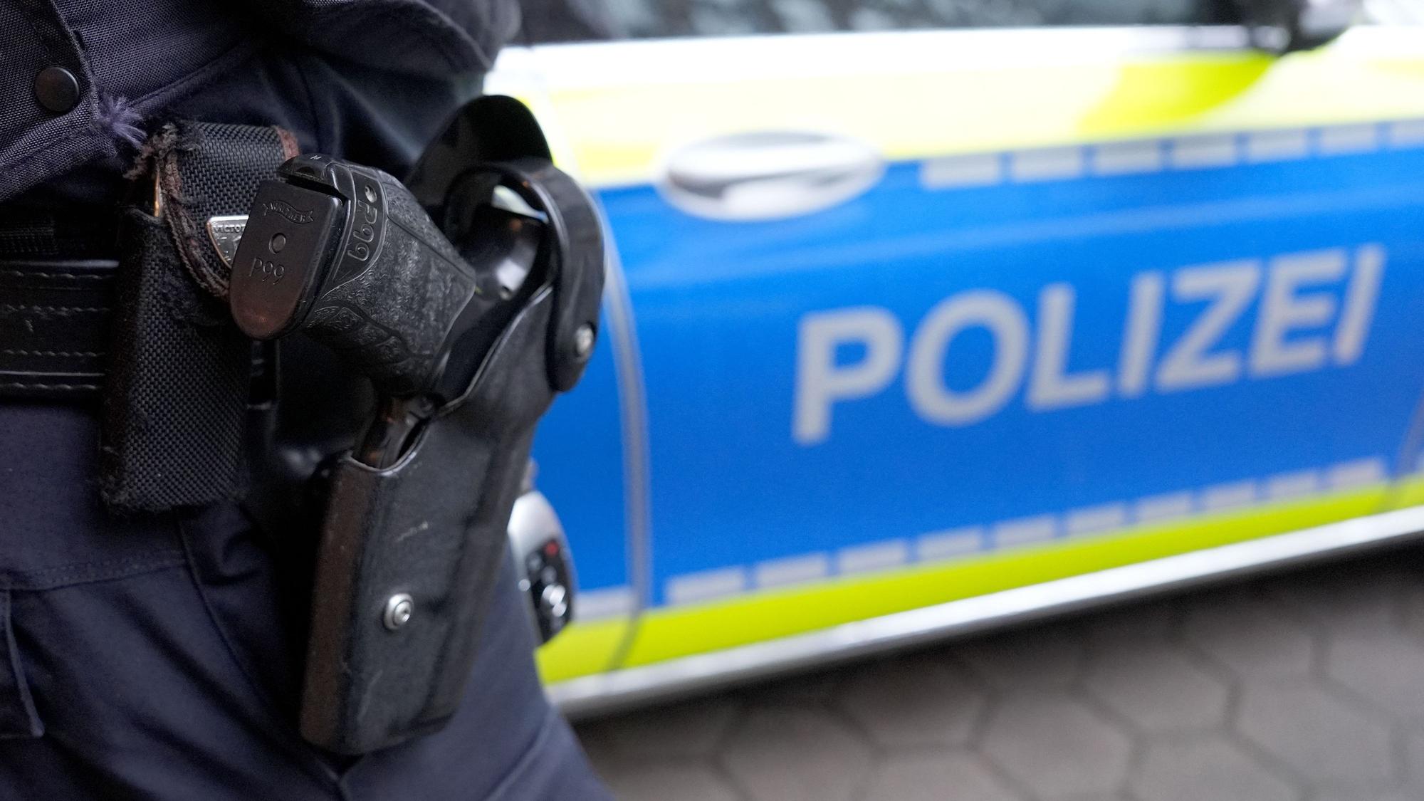 ILLUSTRATION - Ein Polizist steht vor einem Einsatzfahrzeug der Polizei. (zu dpa: «Elfköpfige Gruppe lauert Mann in Sömmerda auf») +++ dpa-Bildfunk +++