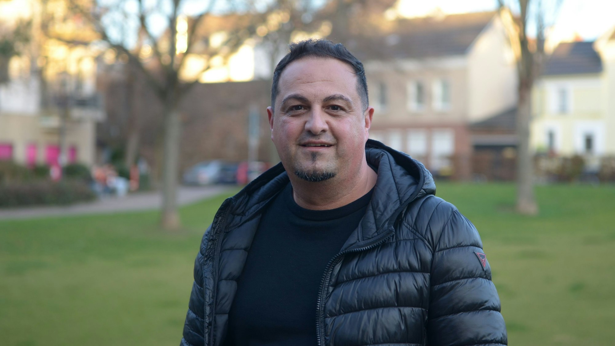 Ein Porträt von Altan Deniz, er steht in einer Parkanlage.