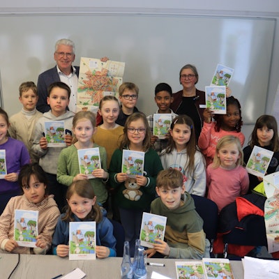 Die Kinder und der Beigeordnete, die sich zu einem Gruppenbild aufgestellt haben, präsentieren den Stadtplan.