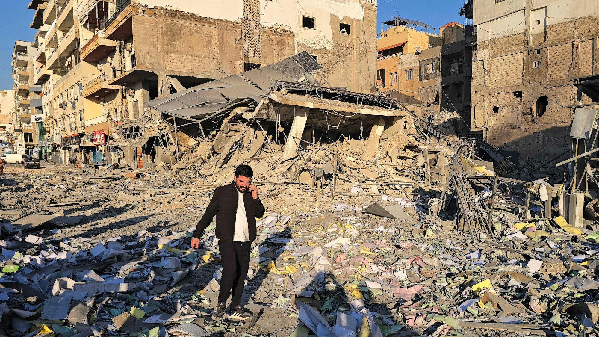 Ein Mann bahnt sich seinen Weg durch die Trümmer am Ort eines israelischen Luftangriffs, der die Büros von Al-Qard al-Hassan, einer mit der Hisbollah verbundenen Finanzinstitution, in der südlibanesischen Küstenstadt Tyros getroffen hat.