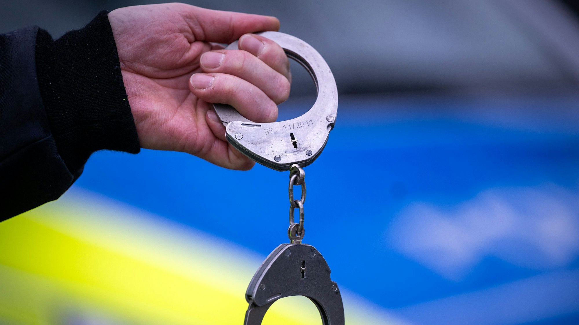 Ein Polizist hält ein Paar Handschellen.