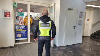 Der Sicherheitsmitarbeiter steht vor einer offenen Tür.