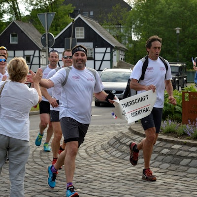 Marathonläufer werden in einem Kreisverkehr von Passanten freudig begrüßt.