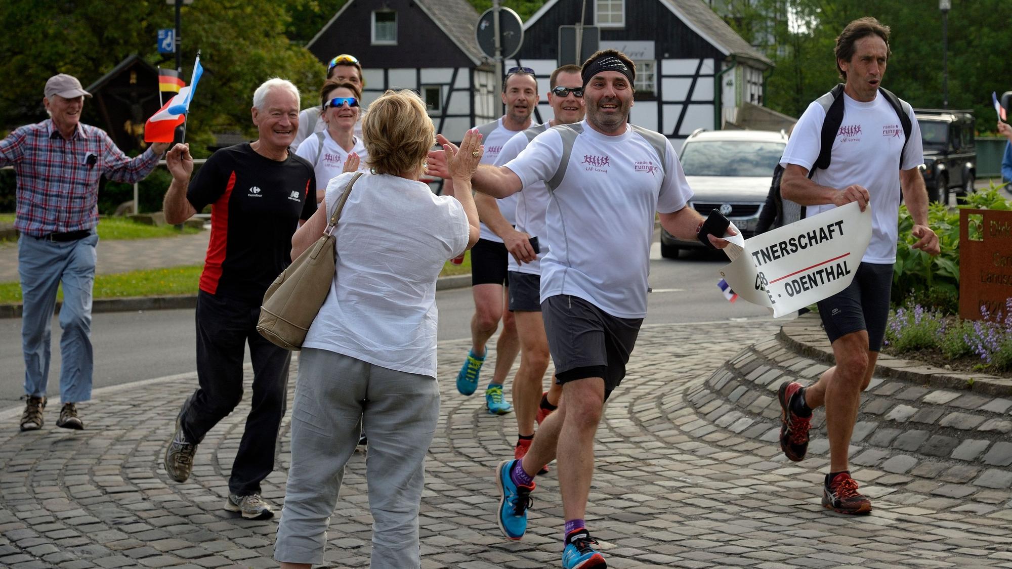 Marathonläufer werden in einem Kreisverkehr von Passanten freudig begrüßt.