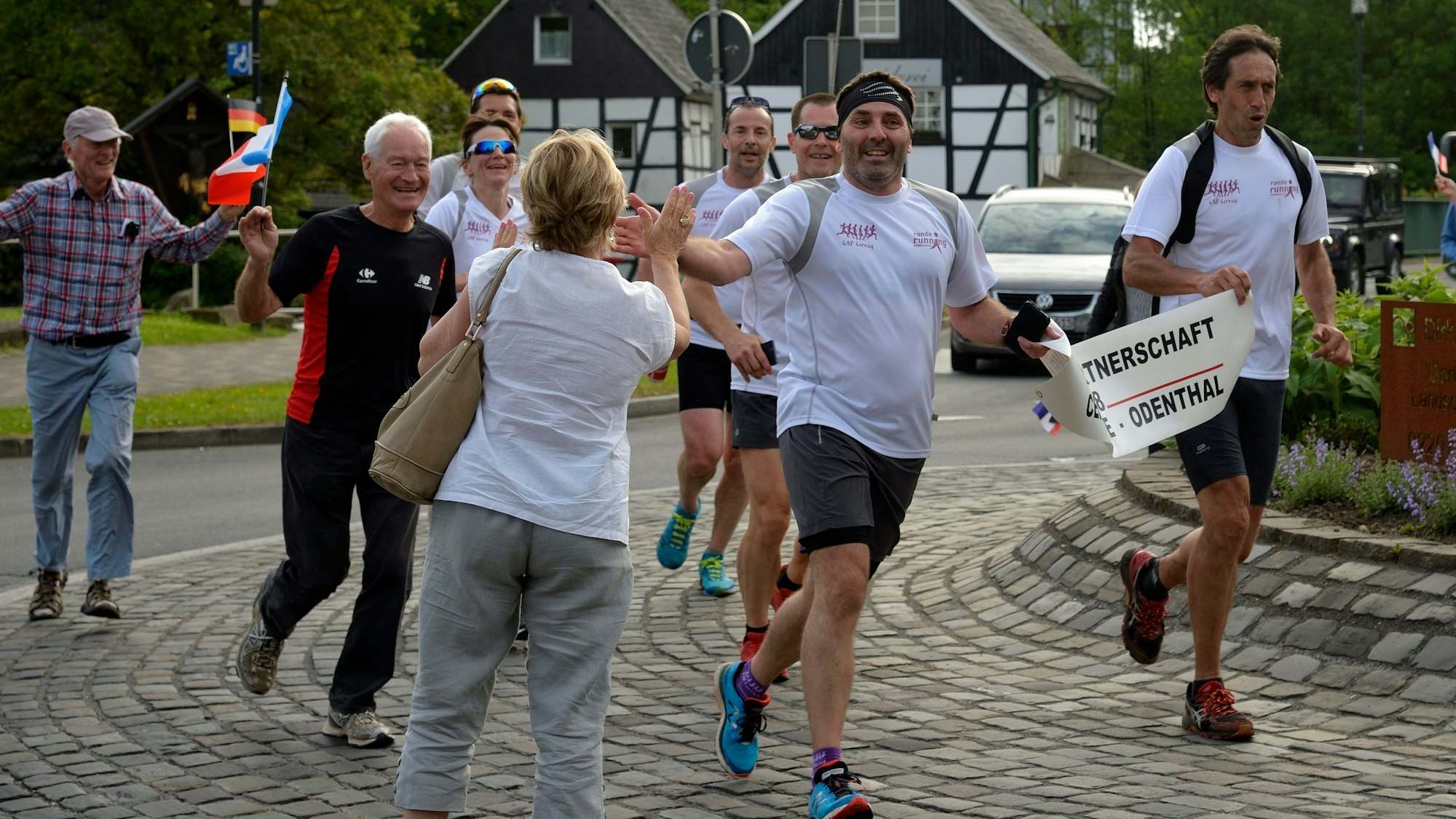 Marathonläufer werden in einem Kreisverkehr von Passanten freudig begrüßt.