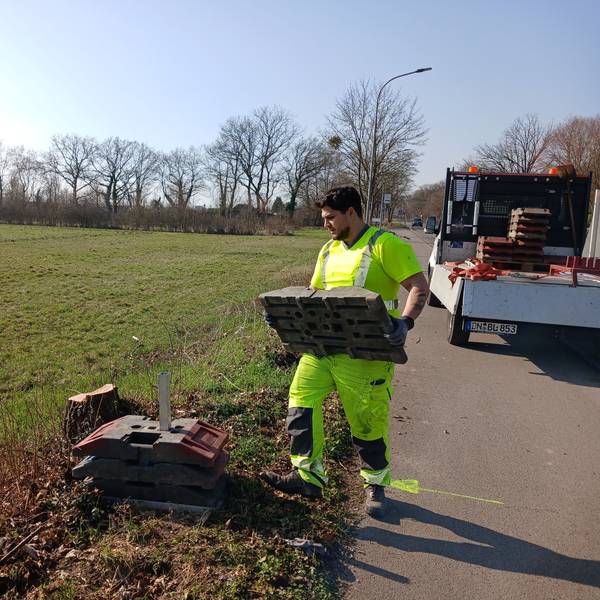 Das Foto zeigt einen Bauarbeiter, der auf einer Wiese Vorarbeiten leistet.