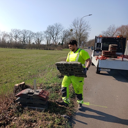 Das Foto zeigt einen Bauarbeiter, der auf einer Wiese Vorarbeiten leistet.
