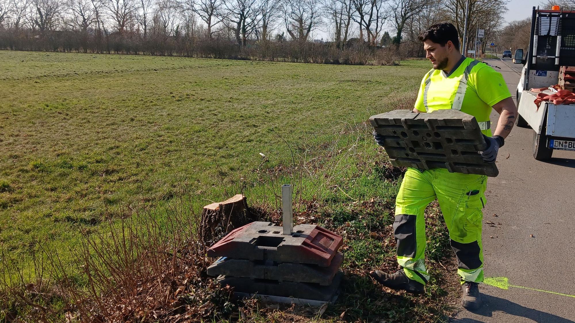 Das Foto zeigt einen Bauarbeiter, der auf einer Wiese Vorarbeiten leistet.