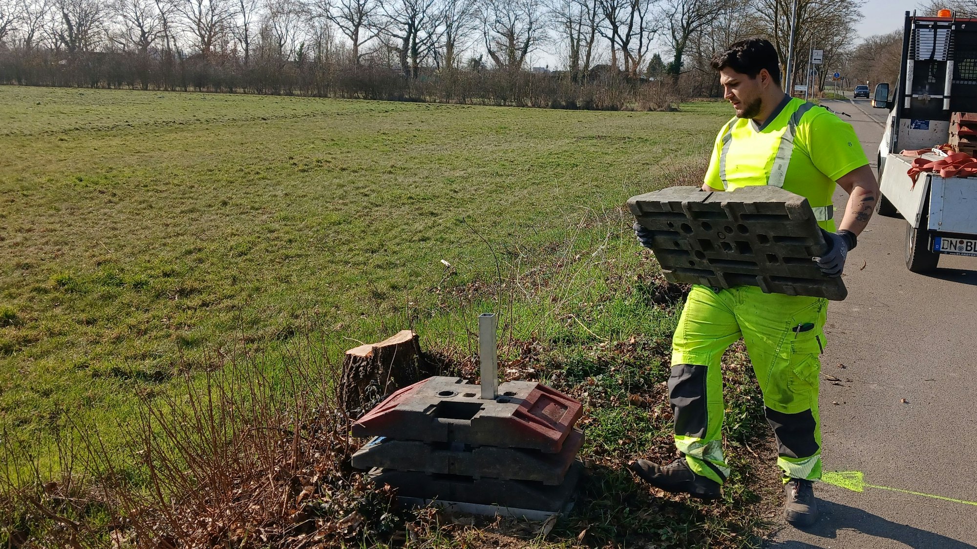 Das Foto zeigt einen Bauarbeiter, der auf einer Wiese Vorarbeiten leistet.