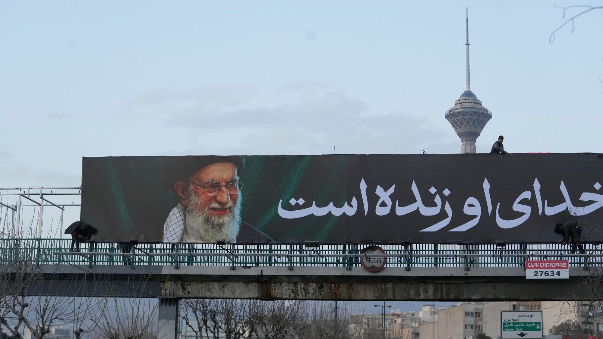 Arbeiter montieren in Teheran eine Plakatwand an einer Überführung mit einem Porträt des getöteten iranischen Obersten Führers Chamenei.