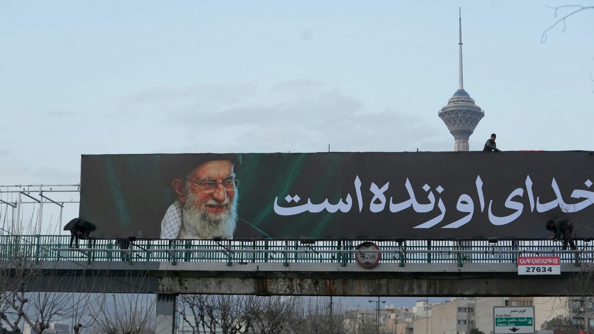 Arbeiter montieren in Teheran eine Plakatwand an einer Überführung mit einem Porträt des getöteten iranischen Obersten Führers Chamenei.