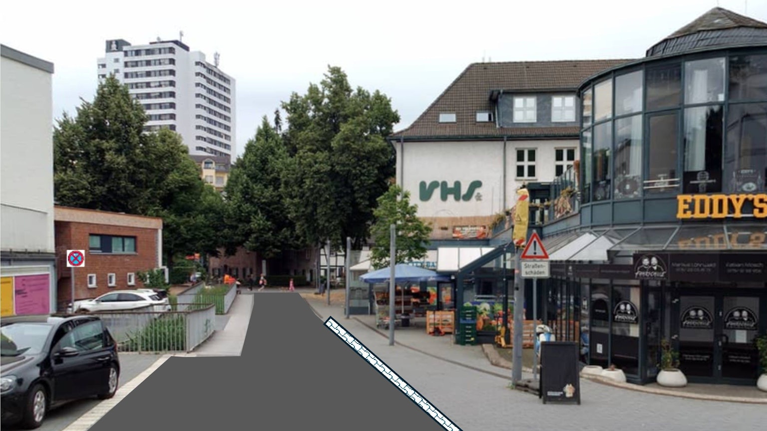 eine Fußgängerzone, auf der linken Seite ist das Pflaster durch Asphalt ersetzt