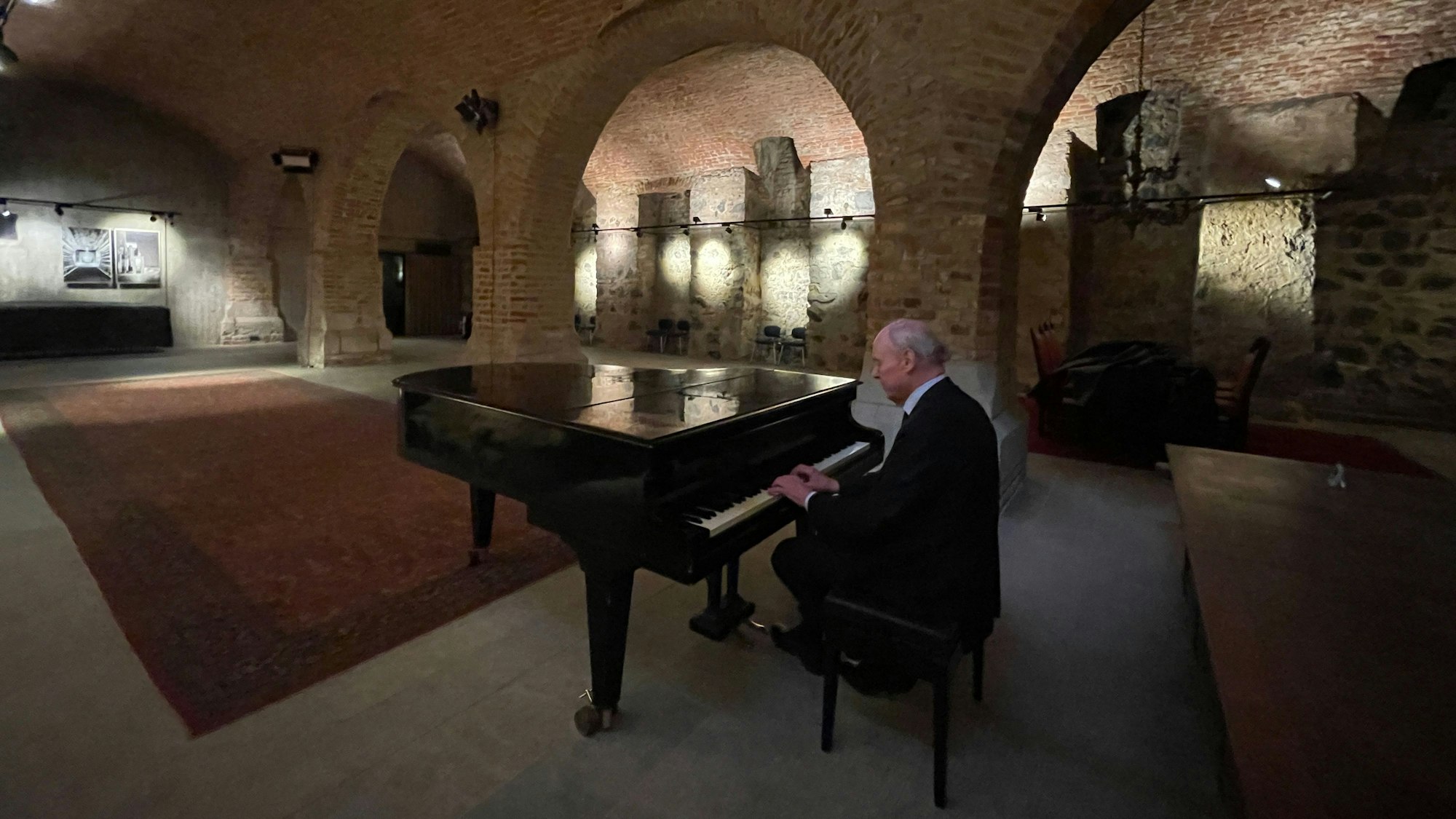 In einem Kellergewölbe sitzt ein Mann an einem Flügel.