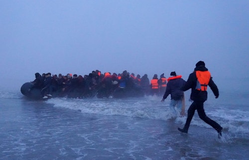 04.03.2026, Frankreich, Gravelines: Menschen, bei denen es sich vermutlich um Migranten handelt, besteigen ein kleines Boot am Strand von Gravelines, Frankreich, während sie versuchen, den Ärmelkanal zu überqueren.