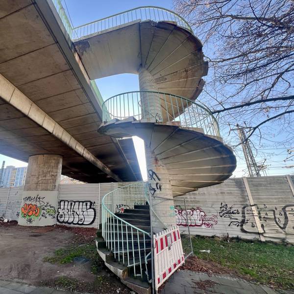 Der Aufgang zu einer Brücke ist mit einer rot-weißen Bake und einem Bauzaun abgesperrt.