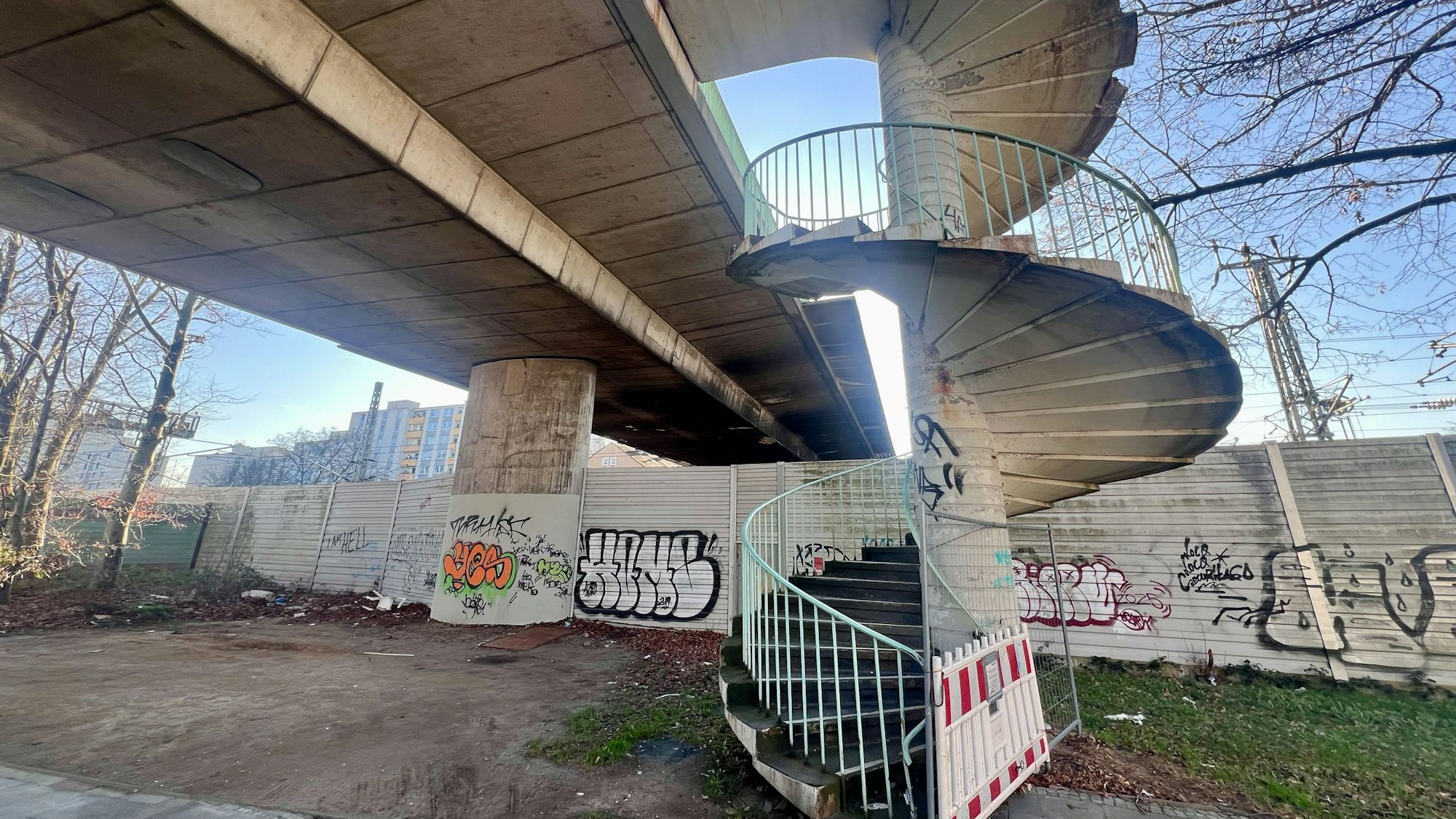 Der Aufgang zu einer Brücke ist mit einer rot-weißen Bake und einem Bauzaun abgesperrt.