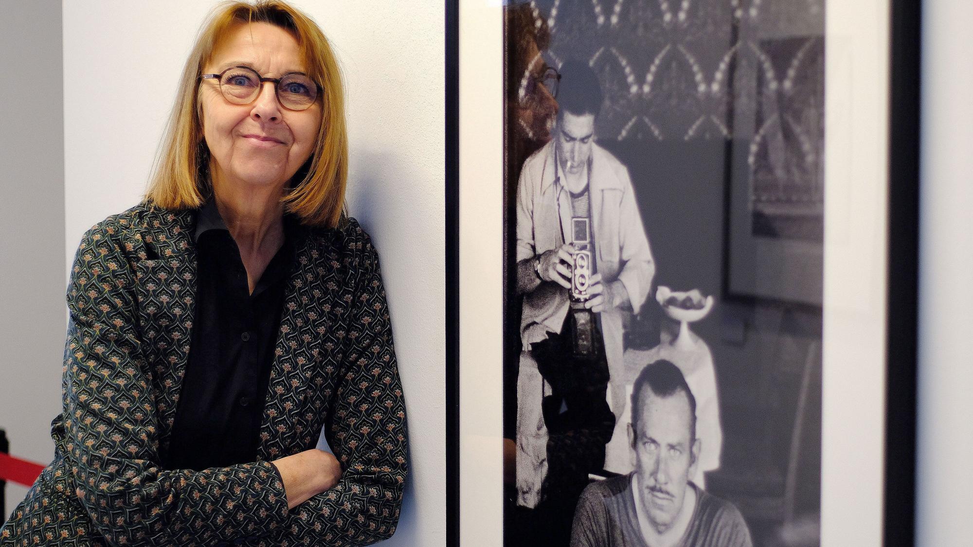 Dr. Nina Mika-Helfmeier, Leiterin und Kuratorin des Fotografie-Forums der Städteregion Aachen in Monschau, steht neben einem Foto, das Robert Capa und John Stinbeck zeigt.