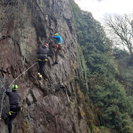 Drei Kletterer begehen in Neuerburg (Eifelkreis Bitburg-Prüm) einen Klettersteig an einer steilen Felswand.