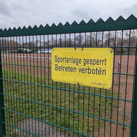 Das Foto zeigt das Hinweisschild „Sportanlage gesperrt“ am Tor des Tennenplatzes in Kendenich.
