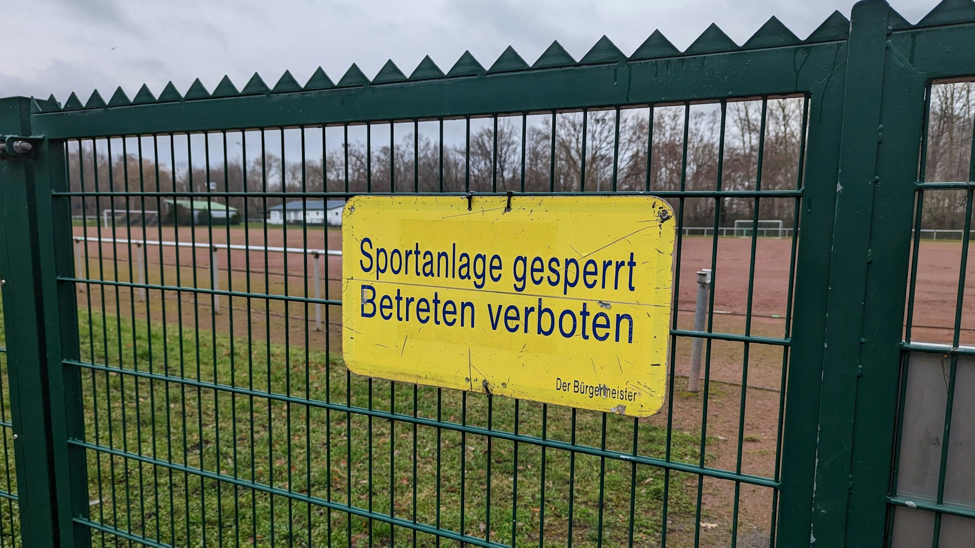 Das Foto zeigt das Hinweisschild „Sportanlage gesperrt“ am Tor des Tennenplatzes in Kendenich.