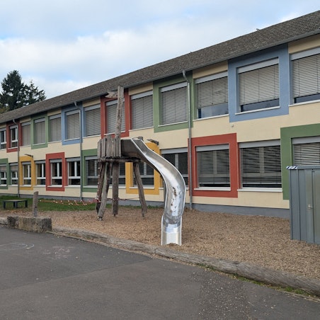 Das Foto zeigt eine Außenaufnahme der Schule und des Schulhofs.