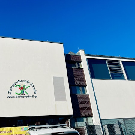 Zu sehen ist ein weißes Grundschulgebäude.