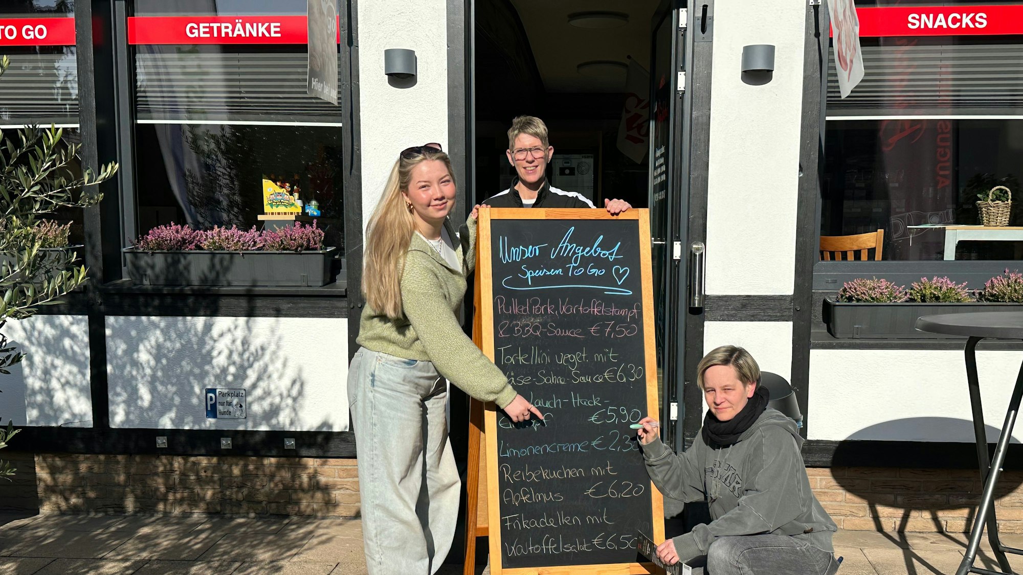 Auf der Tafel vor dem Sankt Augustiner Büdchen findet sich das wöchentliche Angebot.Emelie Schmidt, Michaela Herzog und Angelika Schmitz (v.l.) freuen sich, dass es so gut angenommen worden ist.