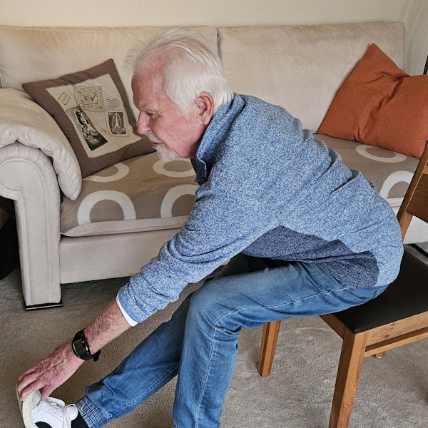 Man sieht eine Hand die sich zu einem Fuß streckt für eine Dehnübung.