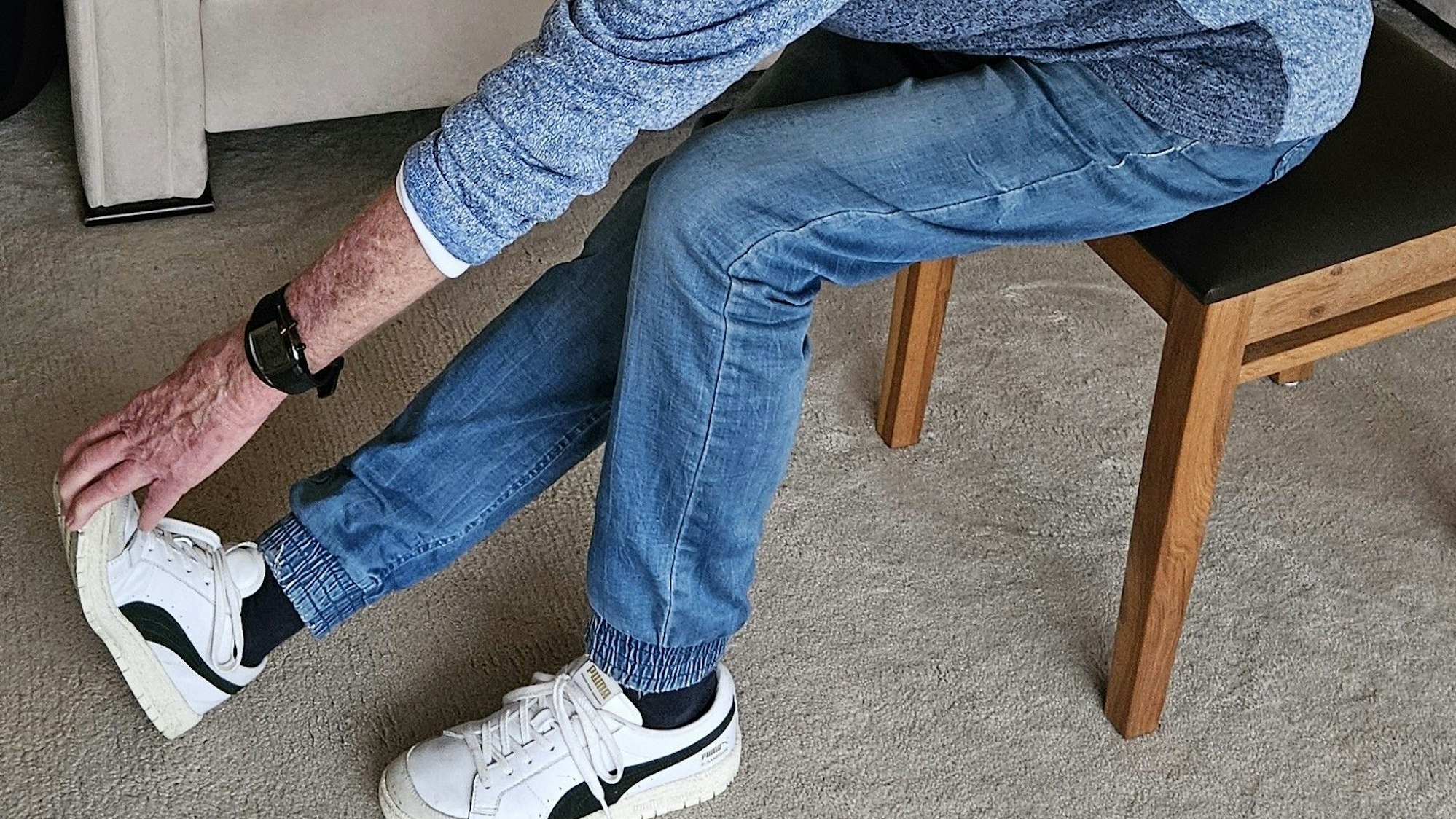 Man sieht eine Hand die sich zu einem Fuß streckt für eine Dehnübung.