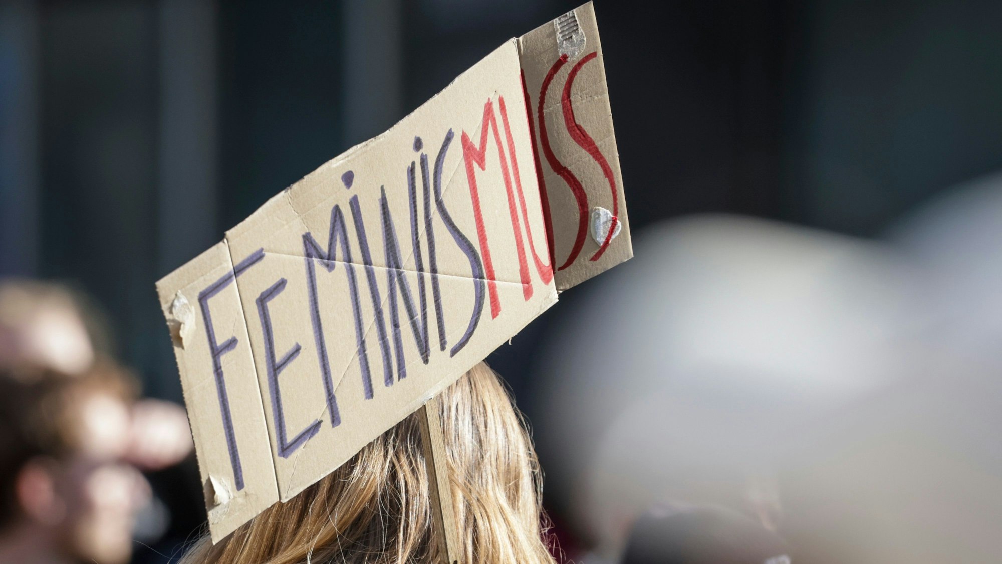 Ein Teilnehmerin einer Demonstration zum Weltfrauentag trägt ein Schild mit der Aufschrift «Feminis-muss».