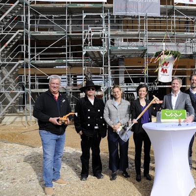 Männer und Frauen stehen vor einem Rohbau.