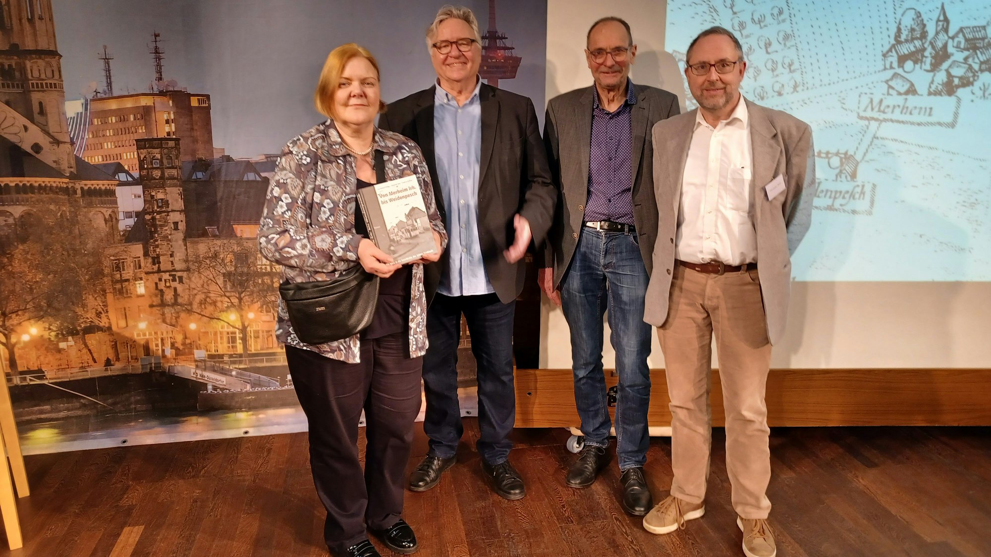 Eine Frau und drei Männer stehen vor einer Leinwand.