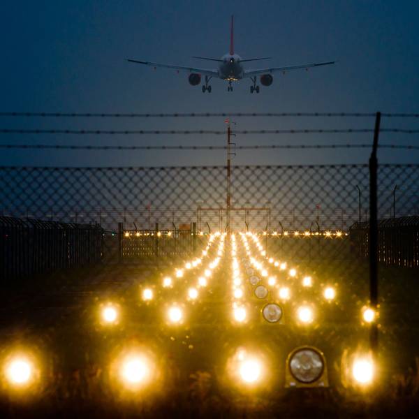 Nacht. eine beleuchtete Landebahn und ein Flugzeug im Anflug.
