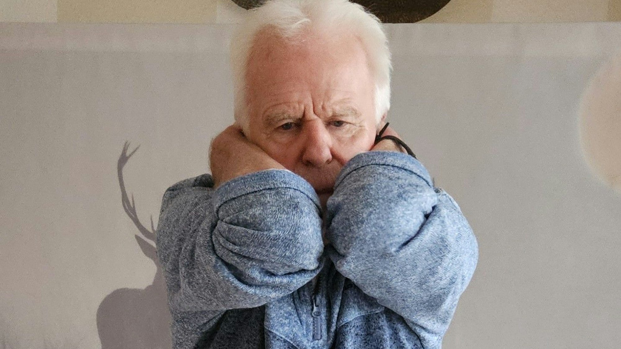 Ein Mann hat die Hände hinten im Nacken und streckt dabei die Ellenbogen nach vorne.