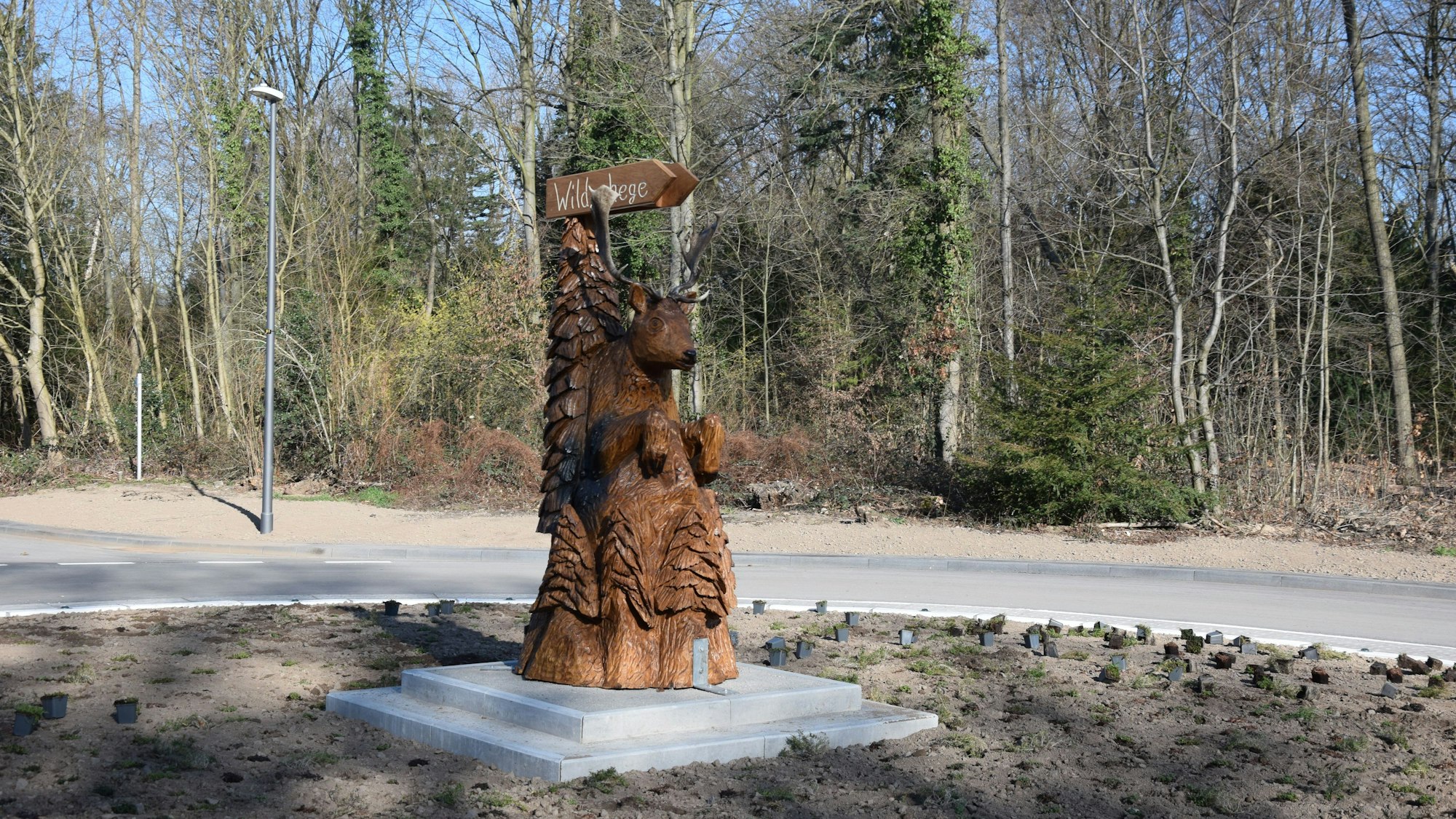 Eine Holzskulptur steht in der Mitte eines Kreisverkehrs.