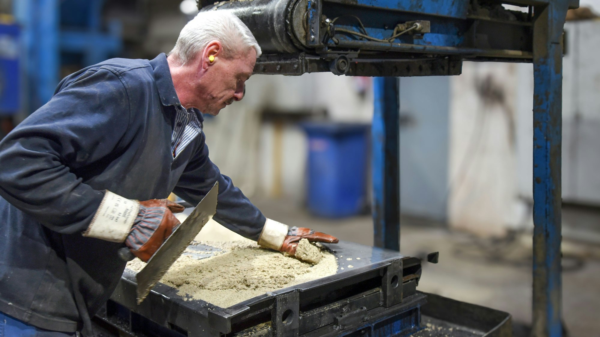 Ein Mitarbeiter fertigt im Gewerbe- und Industriegebiet von Waldbröl-Hermesdorf gerundete Zwischen-Simse aus Beton für die bekannten Gartengrillkamine des Familienunternehmens Buschbeck.
