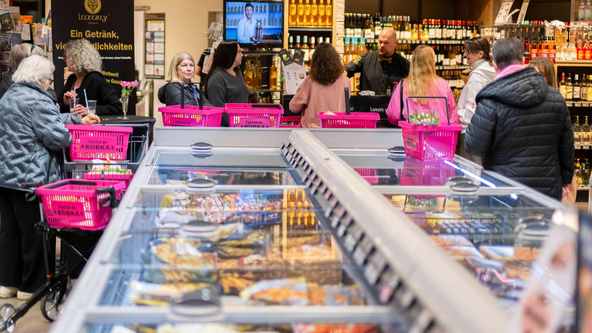 Das Bild zeigt zahlreiche rosa Einkaufskörbe, die auf der Kühltruhe stehen.